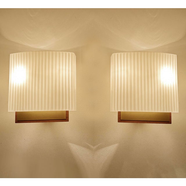 Pair vintage danish modern sconces, featuring a teak and brass support, black enameled back support, slightly rhombic...