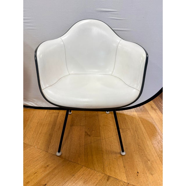 A striking set of four vintage Herman Miller molded shell arm chairs featuring original white upholstery with contrasting...