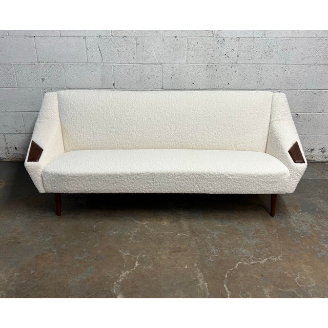 A stunning newly reupholstered in the most amazing boucle fabric sofa with teak accents and amazing sculpted legs....