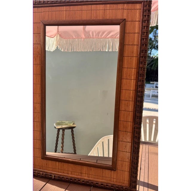 A substantial vintage wall mirror framed in richly toned woven bamboo mat with a clean wood inner border — the kind of...