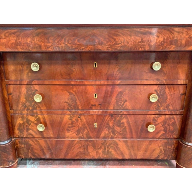 Empire chest of drawers with detached columns. Flamed mahogany veneer on oak backing. Front with four drawers. Previously...