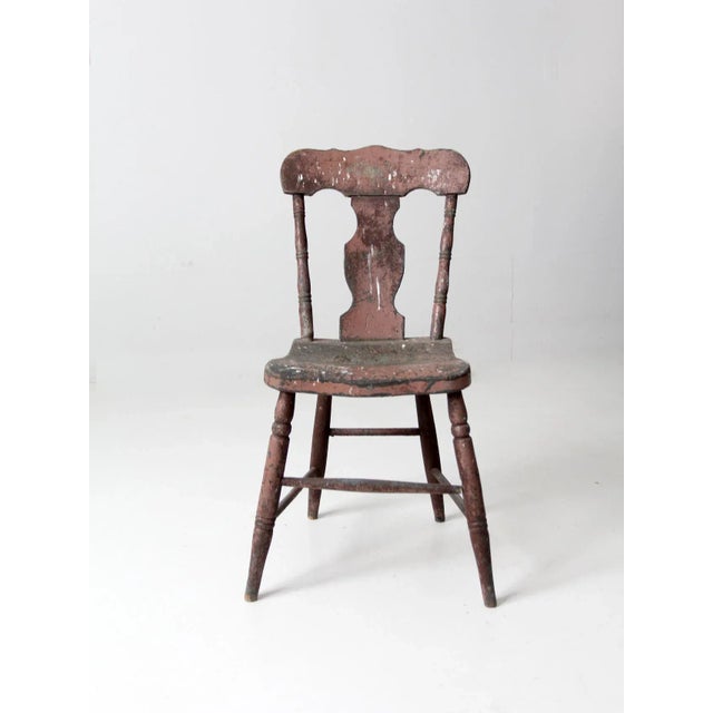 A charming 19th-century primitive farmhouse chair featuring a shaped splat back and gently curved seat. The worn painted...