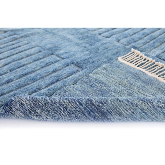 A dense, richly mottled blue field with a subtle linear rhythm running through it — understated, textural, and quietly...