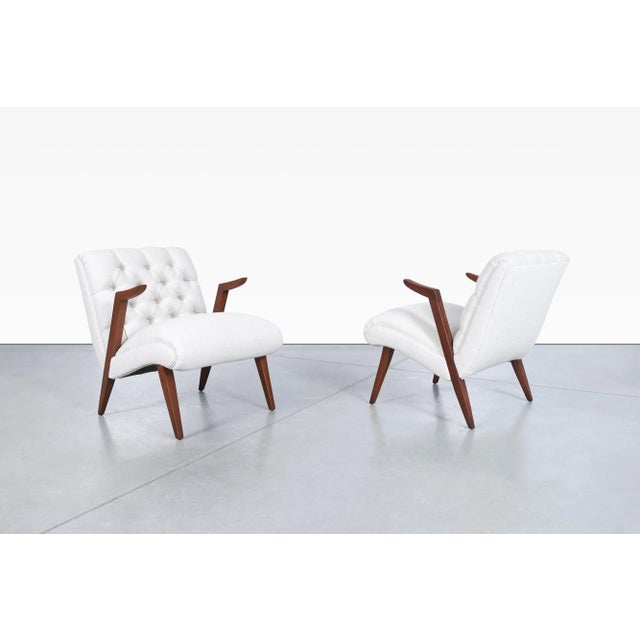 Designed and manufactured in the United States during the 1950s, these mid-century modern walnut lounge chairs embody the...