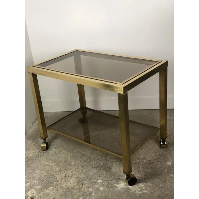 Brass sideboard / rolling table with two shelves of smoked glass trays. 4 casters. Italian design vintage 1970 Stitched on...