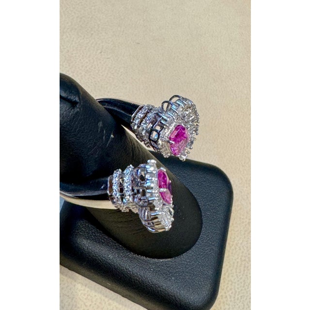 The 2.5 Ct Pink Emerald Cut Pink Sapphire & 2.8 Ct Diamond 18 Kt White Gold Ring in Size 6 is a classic piece with two...