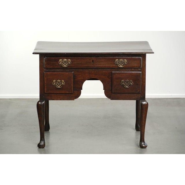This antique English lowboy/side table dates from the 18th century and is made of oak. The side table has a luxurious look...
