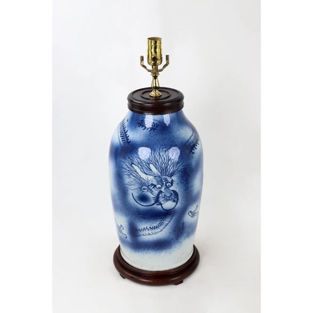This Blue & White porcelain vase lamp depicts a dragon wrapped around the vessel, with blue cobalt sprayed around it.