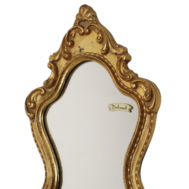 Small vintage mirror with a decorative crest in the classic Baroque style, crafted from wood and gesso gilded with gold...