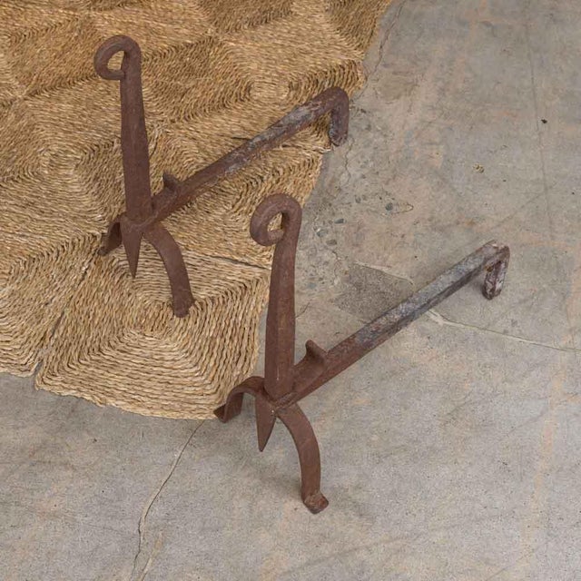 Lovely pair of wrought iron andirons from France, 1950s. Heavy forged iron with arched base and loop detail. Surface shows...