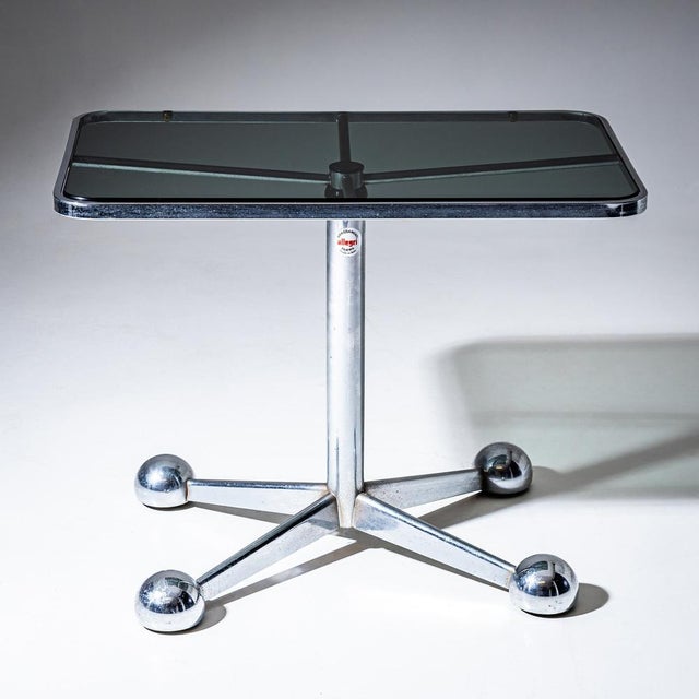 Glass table featuring a rectangular clear-glass top with rounded corners. The structure incorporates a cross-shaped...