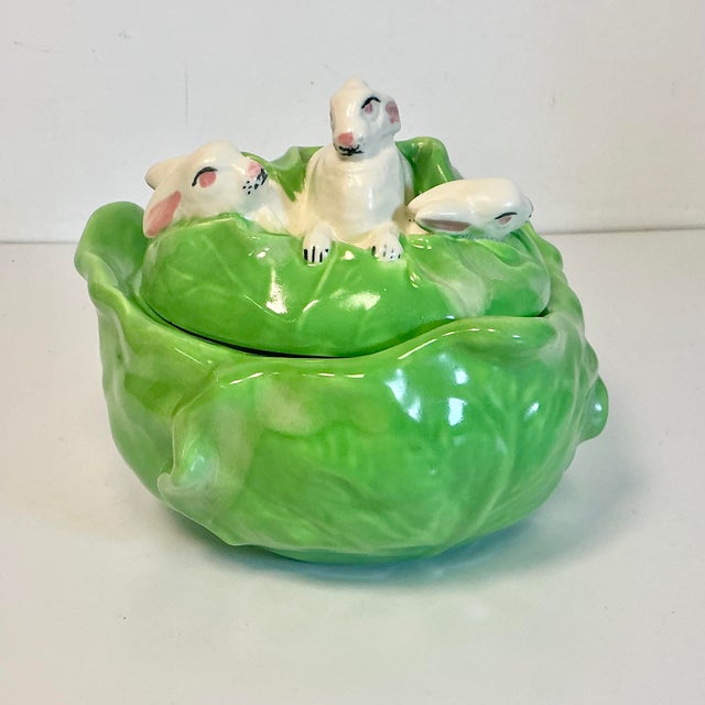 This Americana Folk Art Ceramic Tureen features a cabbage and three bunnies nestled in the cabbage leaves on the lid. The...