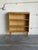 This oak bookcase has a compact upright profile with three open display levels. A scalloped trim runs beneath the raised...