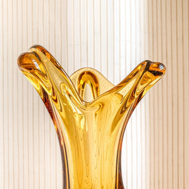The heavy, teardrop base rises into a slender waist and opens into a dramatically pulled, three-pointed rim. Thick clear...
