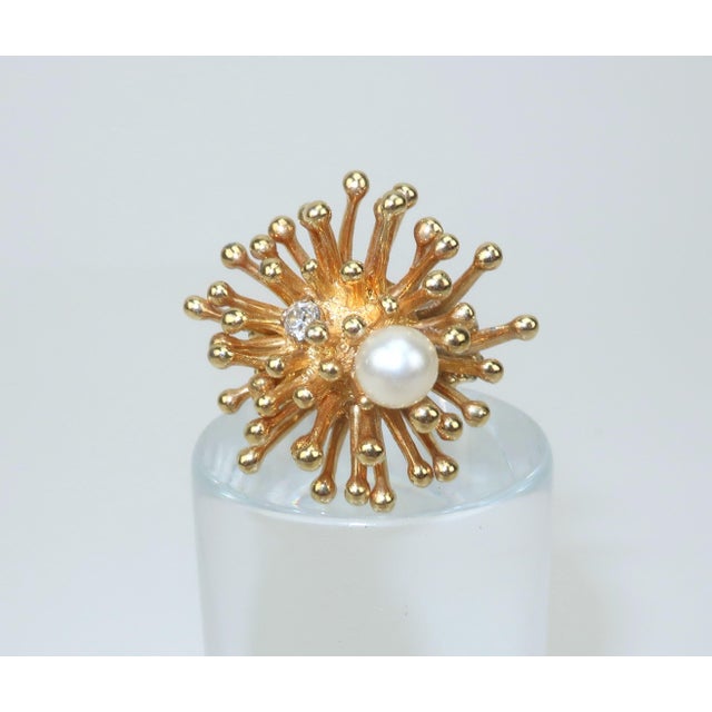 C.1970 Sarah Coventry cocktail ring with a starburst style in a gold tone metal accented by a faux pearl and rhinestone....