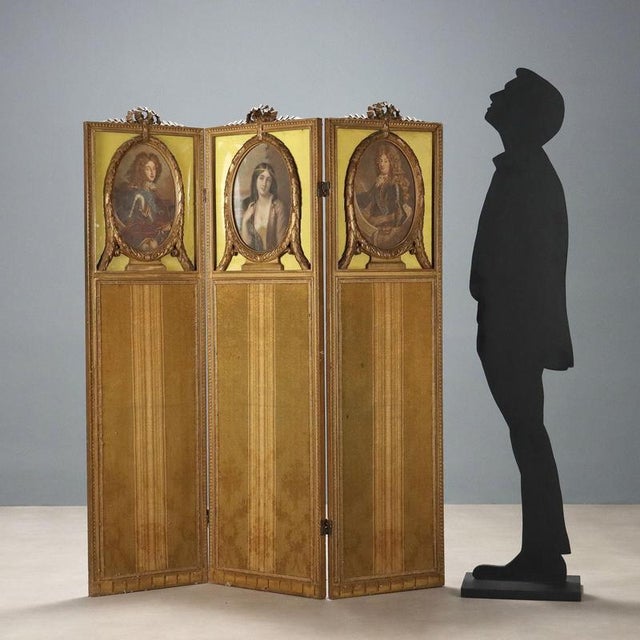 Gilded wooden folding screen. Two male figures on the side panels and a female figure in the center, surrounded by leaf...
