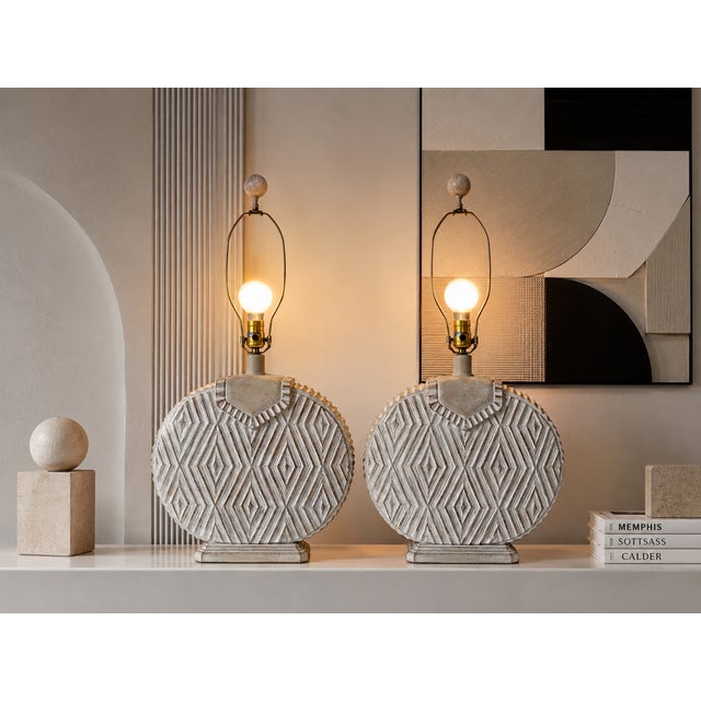 A striking pair of 1980’s Postmodern table lamps featuring sculptural round plaster bodies with raised geometric diamond...