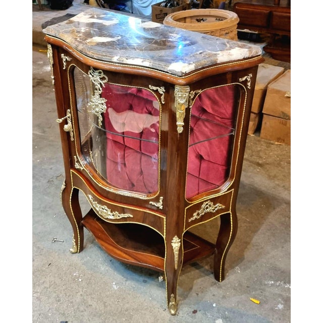 Elegant and richly detailed, this French Louis XV-style display cabinet is crafted from solid wood and designed to...