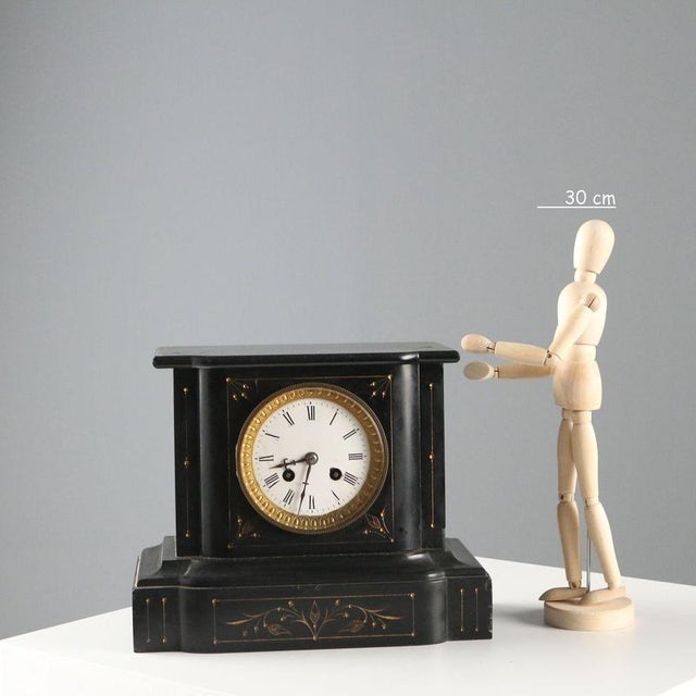 Black marble table clock with engraved and gilded decorations. Enamelled metal dial with Roman numerals, protected by a...