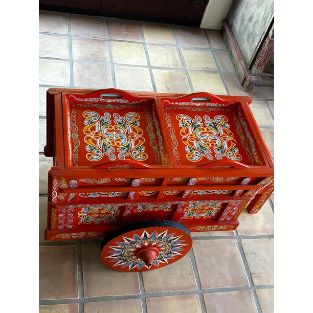 This handcrafted Costa Rican oxcart features intricate, colorful folk art designs painted on a red wooden frame. Stunning...