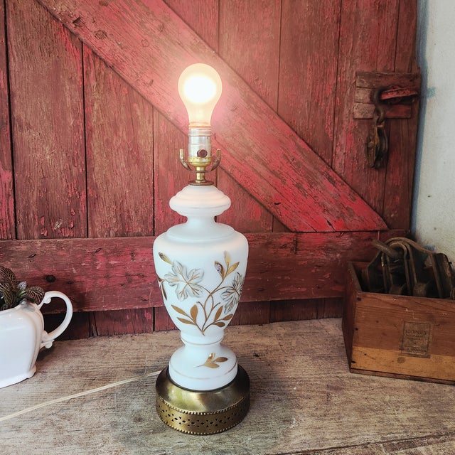 This vintage table lamp features elegant milk glass with a delicate gold floral design and brass accents. Its timeless...