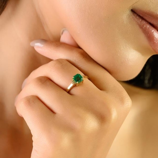This elegant solitaire ring showcases a certified 1-carat square-cut natural emerald measuring 5 mm, set in luminous 14K...