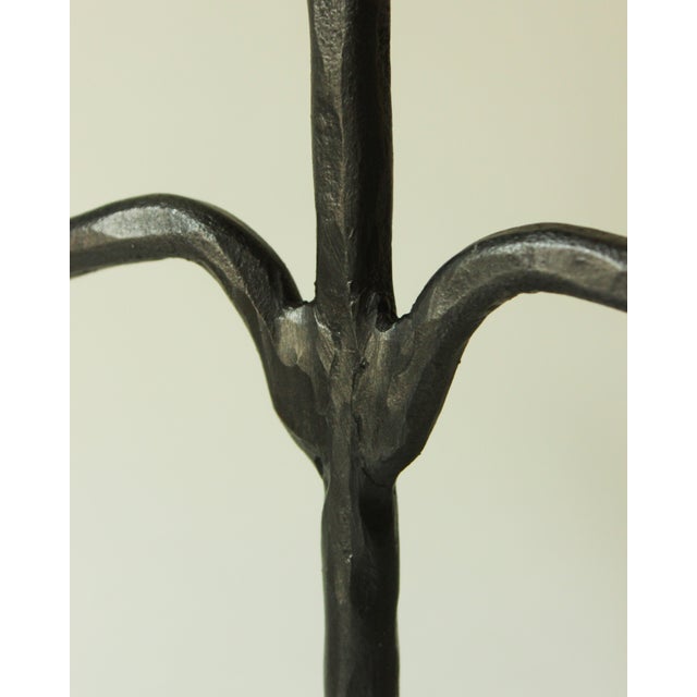 Pair of hammered wrought iron candlesticks with a black wax patina, featuring three arms and tripod bases. French...