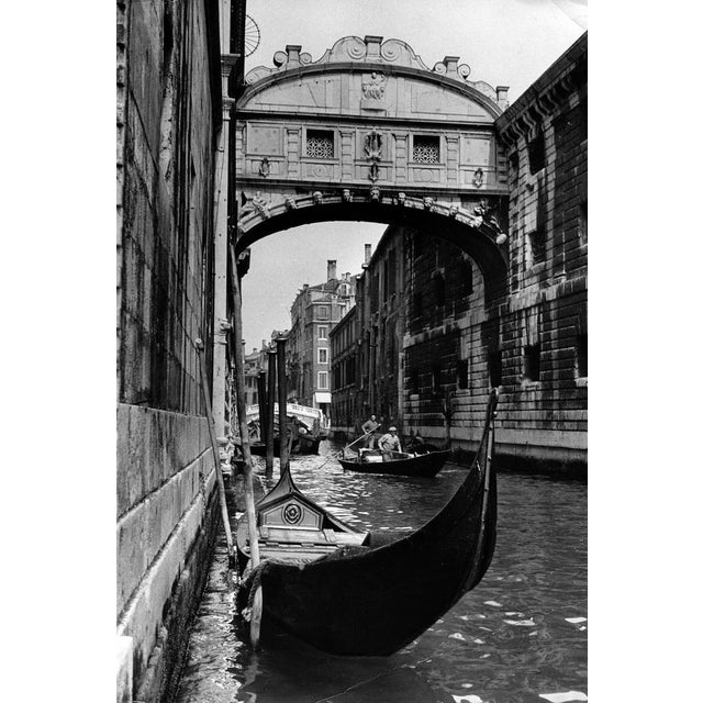 The black-and-white photograph features a captivating view of the Ponte dei Sospiri (Bridge of Sighs) in Venice, taken in...