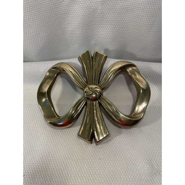 A lovely solid brass Bow Trivet or Wall Ornament from mid to late 20th century. No markings. This adorable knotted bow has...