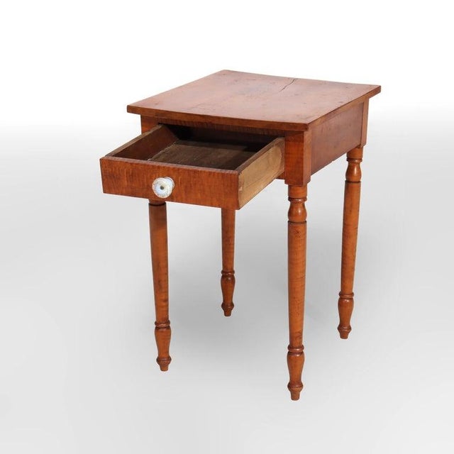 An antique single drawer side stand, crafted from highly figured tiger maple wood, dating to approximately 1830. This...
