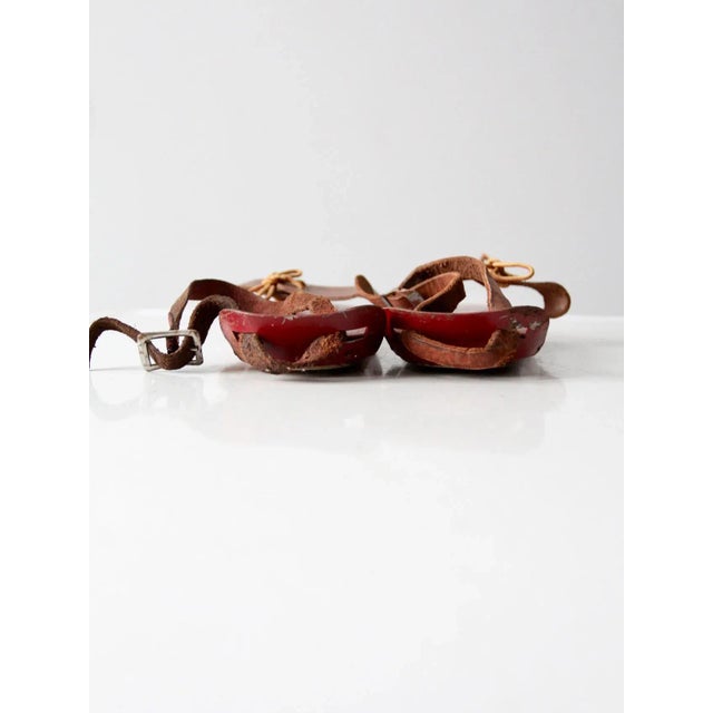 This is a pair of antique wooden ice skates. A rare find, the red wood base skates have two slender metal gliding blades...