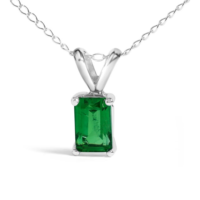 Draped in the regal splendor of a color-enhanced, natural emerald, this 14K white gold pendant necklace exudes elegance...
