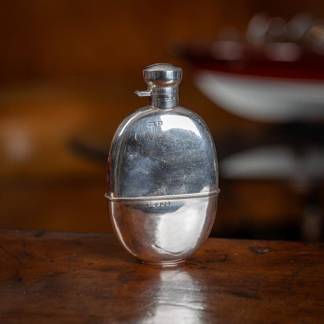 A superb 20th Century solid silver hip flask with silver hinged top. The flask features a smooth surface and a round oval...