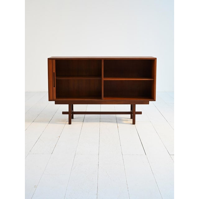 Teak cabinet with tambour door, open compartment with internal shelf, and base with central crosspiece. Scandinavian...
