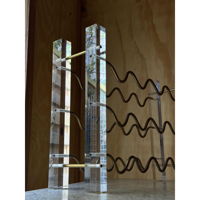 Stunning vintage 1970s countertop wine rack featuring thick clear acrylic glass upright pillars and sinuous brass-toned...