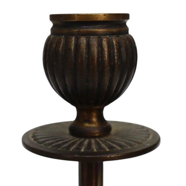 This is a pair of antique patinated bronze candlesticks, dating to approximately 1920. Each candlestick features a fluted...