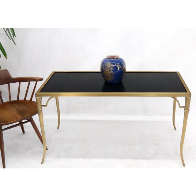 Heavy grade materials coffee table made of solid black granite top and solid brass frame with tapered legs.