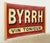 The sign is painted on a red background with off white colored letters that reads "BYRRH VIN TONIQUE" which translates to...