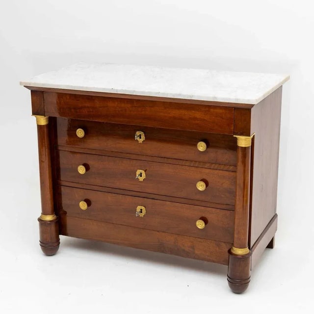 French Empire chest of drawers in Mahogany veneered, with four drawers and white marble slab. The body is flanked by...