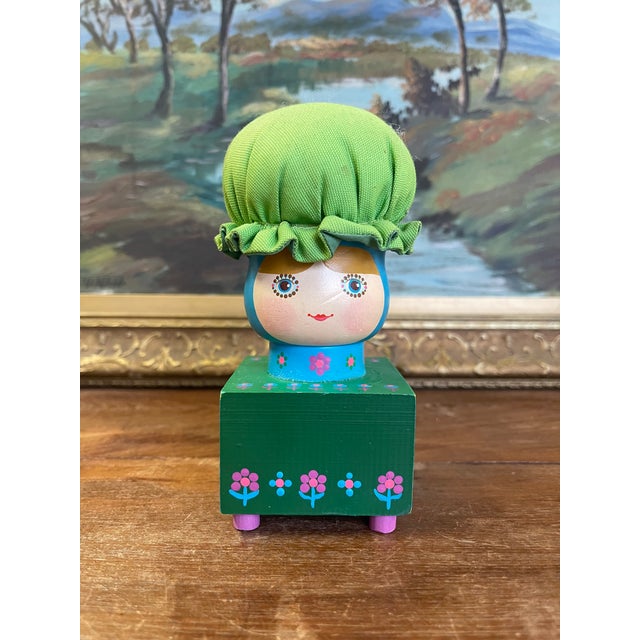 Charming vintage hand-painted folk art figurine featuring a stylized doll perched atop a square wooden block base.The...