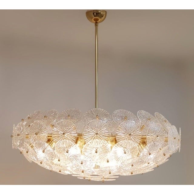 A dramatic oversized pair of Italian Loto chandeliers, circa 1970s, composed of layered textured clear Murano glass discs...