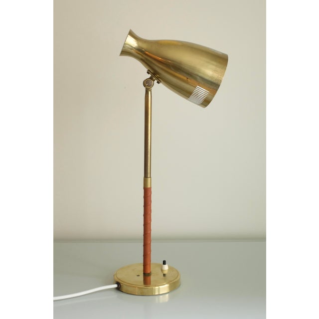 Circa 1950s Brass and Leather table lamp model E1247 by ASEA Belysning, Sweden. Decorative brass perforated lampshade with...