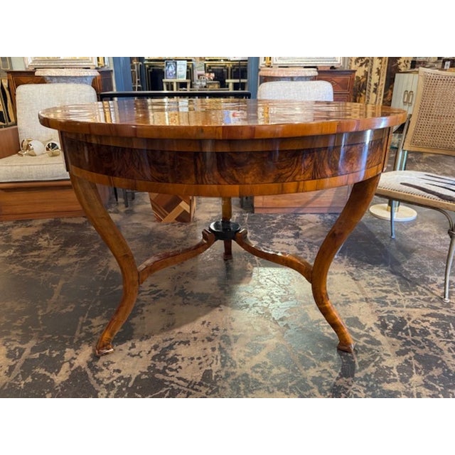 The 19th Century German Walnut Biedermeier Center Table is a classic and elegant piece of furniture that would make a...
