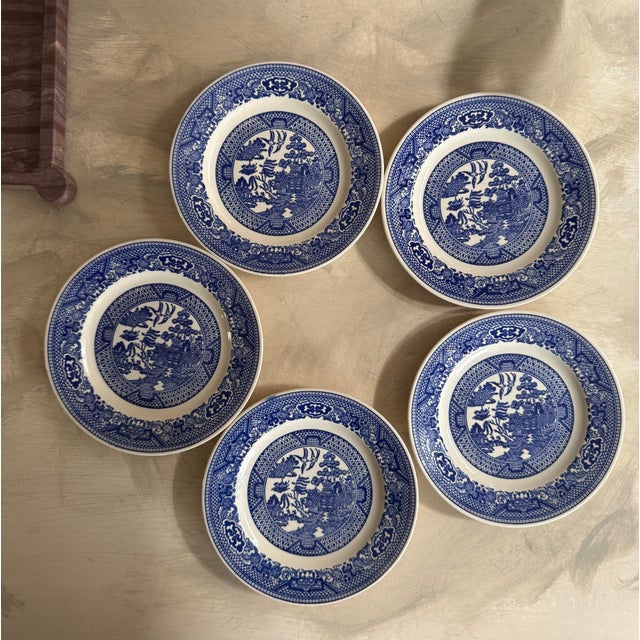 A timeless set of five vintage Blue Willow plates, featuring the iconic chinoiserie landscape with pagodas, bridges, and...
