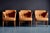 Set of three elegant 1950s lounge chairs with sculptural curved armrests, tapered wooden legs and newly upholstered cognac...