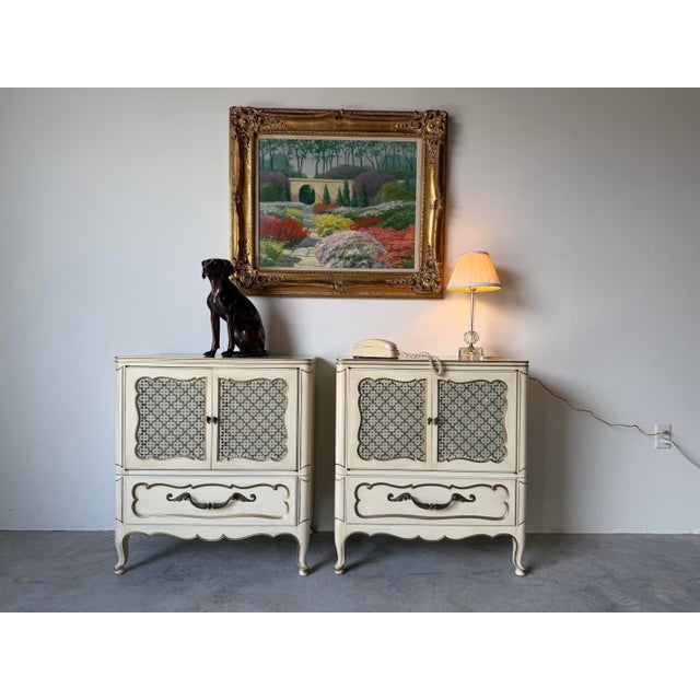 Elegant vintage pair of Grosfeld House French Provincial Louis XV-style nightstands featuring a beautifully distressed...