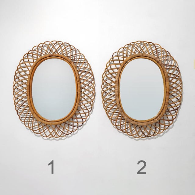 A wall mirror from the 1950s characterised by an oval rattan frame composed of a succession of curved elements radiating...