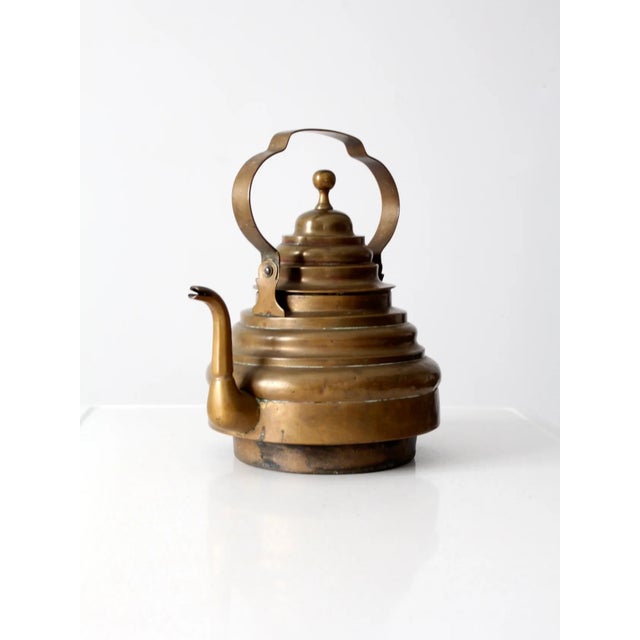 This is an antique brass teapot. The decorative tea pot features a striking stepped design with knobbed lid and swing...