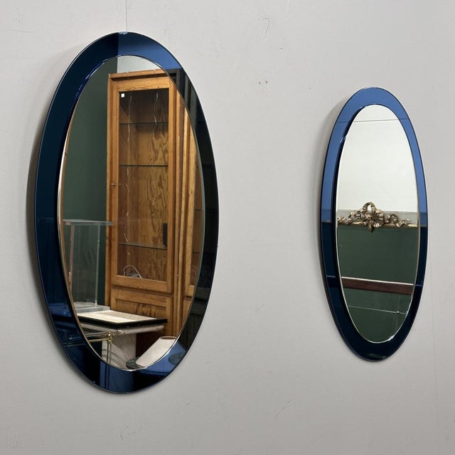 A striking pair of Italian blue oval mirrors, attributed to Cristal Arte, dating from the 1970s. Each mirror features a...