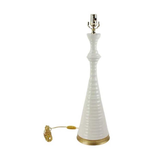 An elegant glazed ceramic table lamp by Hwang Bishop, handcrafted in glossy white with a gilt base. The lamp’s slender...